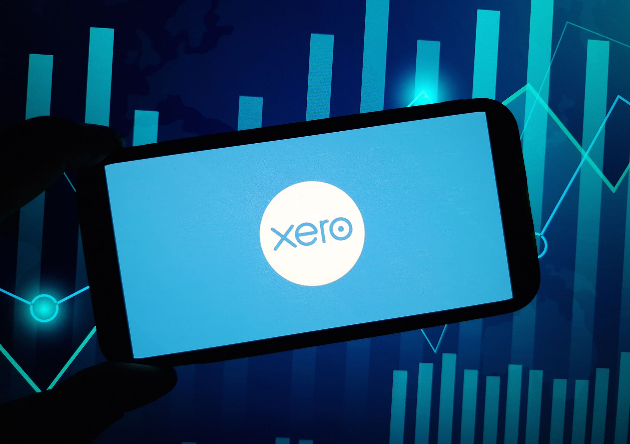 Xero logo in tablet screen with graphs in the backgruond