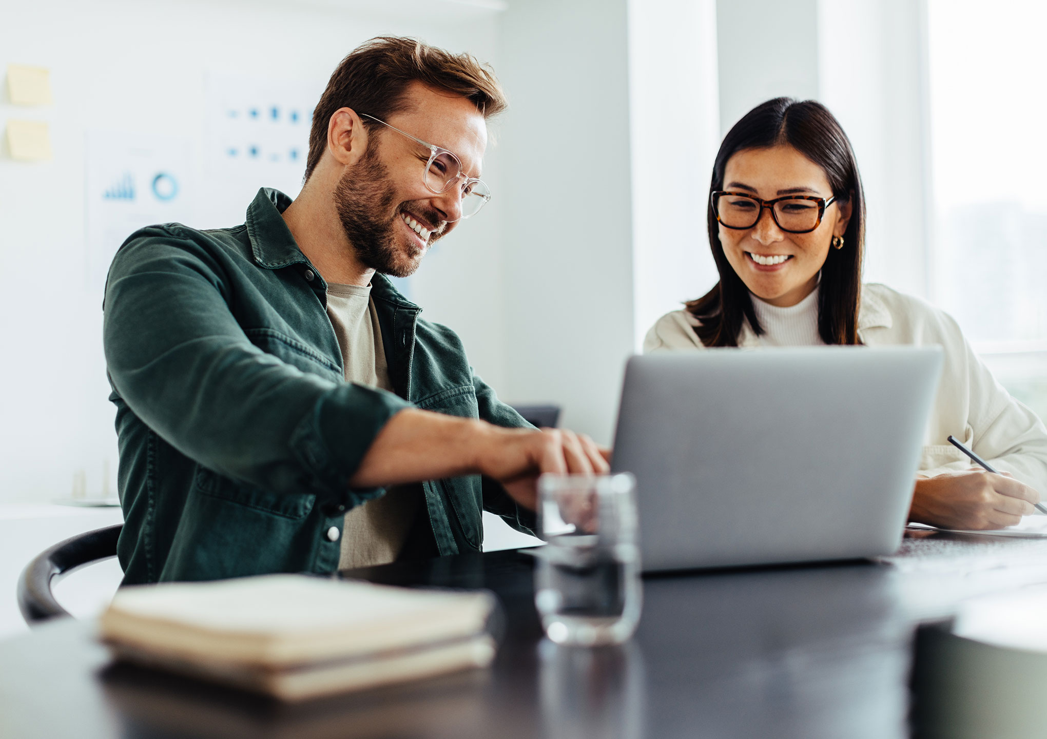 Two business people using a laptop together while sitting in a meeting.